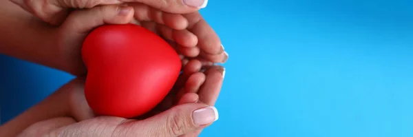 Close-up in female palms childrens hands and heart — Stockfoto