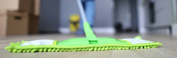 Male hand with yellow protective gloves hold green plastic mop