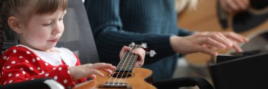 Ebeveynler bebeğe birlikte gitar çalmayı öğretir.