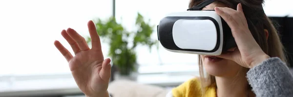 Mädchen sitzt zu Hause und schaut durch eine virtuelle Brille — Stockfoto