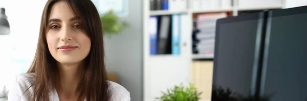 Hermosa empleada sonriente sentada en el lugar de trabajo — Foto de Stock