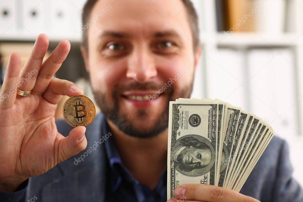 Cheerful young man holding gold coin and money