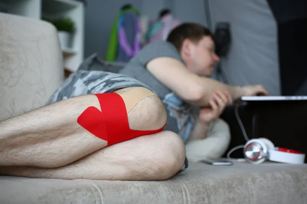 무릎 부상을 입은 채 소파에 누워 있는 청년 — 스톡 사진