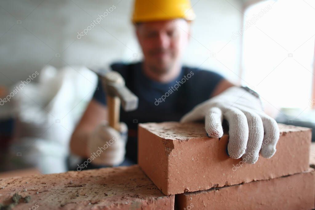 Male worker in gloves building brick wall