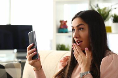 Evde cep telefonu kullanan genç bir kadın.