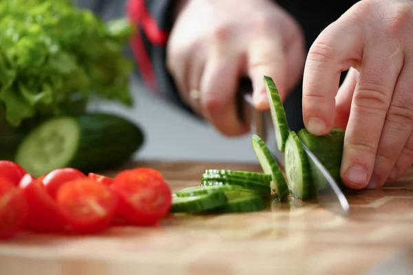 Jovem cortando pepino fresco com faca — Fotografia de Stock