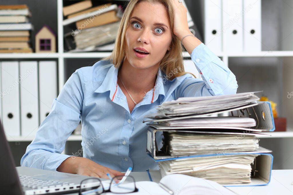 Astonished young woman having a lot of work in office