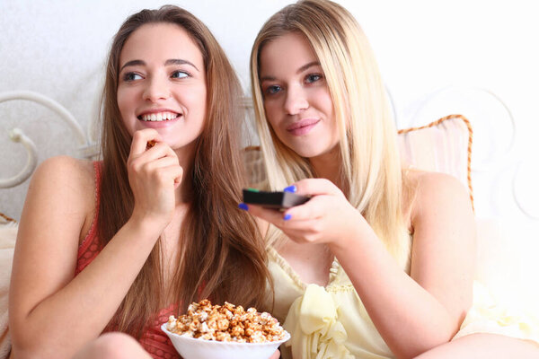 Cheerful female friends watching movie together at home