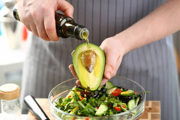 Mannelijke handen gieten olijfolie op avocado — Stockfoto