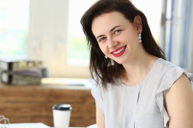 Çekici esmer kadın kameraya bakıyor ve gülümsüyor.