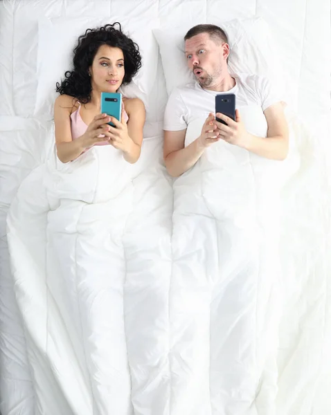 Wife and husband lie on bed top view portrait