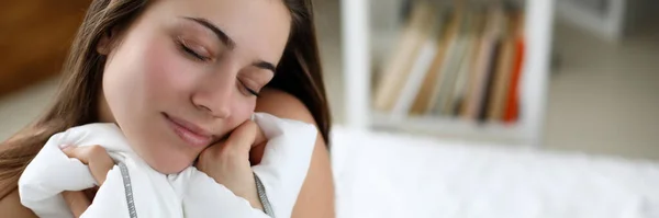 Flicka sittande på vit säng med slutna ögon vilar — Stockfoto