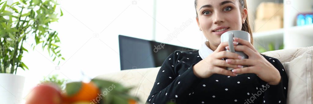 Girl sitting on sofa with cup in her apartment