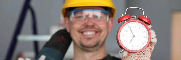 Masculino construtor capacete rindo mostrando despertador relógio — Fotografia de Stock