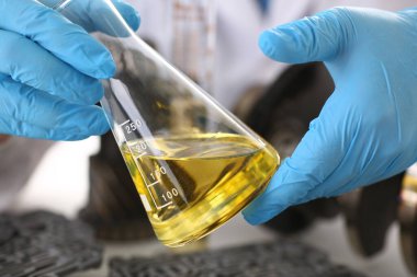 Koruyucu üniformalı bir laboratuvar asistanı ve reaktif matarası.