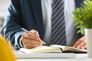 Takım elbiseli ve kravatlı bir işadamı elinde gümüş kalemle