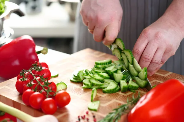 Homem cortando legumes para salada em casa — Fotografia de Stock