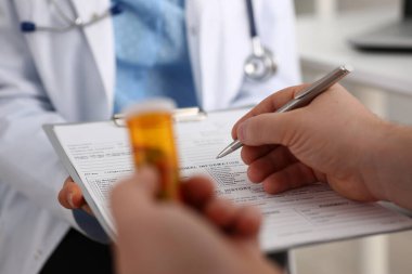 Adam doktorla konuşurken kavanozda hap tutuyor.