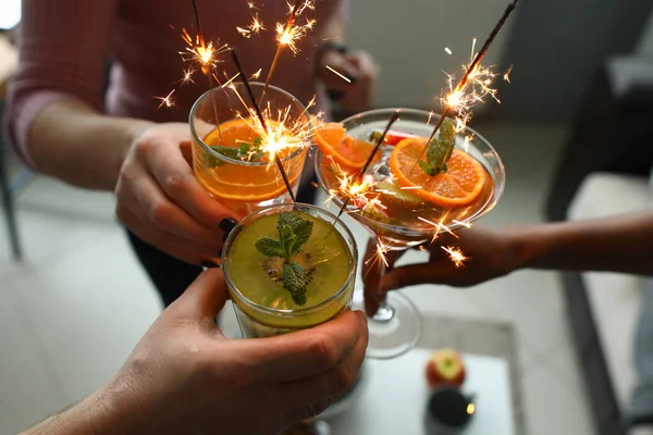 Goup of people holding cocktails in their hands with sparklers