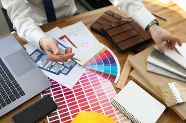 Ofisteki adam masasında iç mekan için renk paletiyle oturuyor.