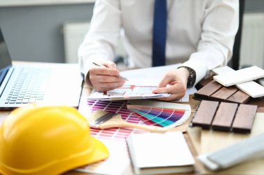 Ofisteki tasarımcı proje ve iç mekan için bir renk paleti ile masada oturur