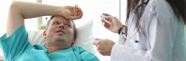 Female doctor preparing dropper for male patient — Stock Photo, Image