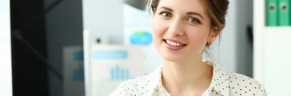 Mulher sorridente bonita sentada no escritório olhando na câmera — Fotografia de Stock