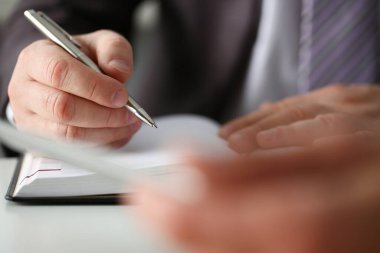 Takım elbiseli bir işadamı ofiste kağıtları imzalıyor.