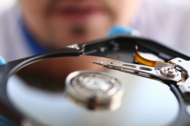 Bilgisayardan küçük disk okuyucuya bakan adam