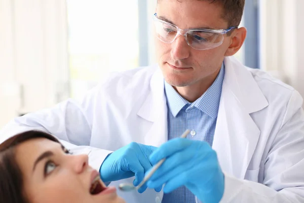 Мужчина-дантист осматривает женские зубы во время посещения — стоковое фото