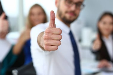 Yöneticilerin önünde baş parmağını gösteren bir adam.