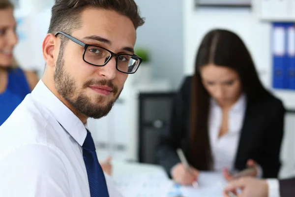 Handsome smiling bearded man working with colleagues in office — Stock Photo, Image
