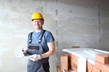 Sarı kasklı mutlu adam inşaatta çalışıyor.
