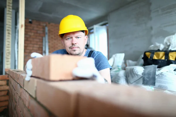 Homem barbudo em capacete que coloca tijolos dentro de casa — Fotografia de Stock