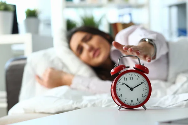Сонная женщина выключает будильник утром — стоковое фото