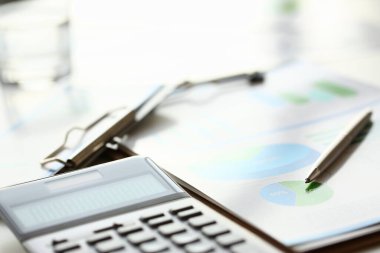 Muhasebeci çalışma masasına pesonal cihazlar ve kağıtlar bırakmış.