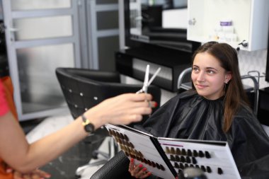 Müşteri güzellik salonundaki saç boyama için numune kitabından boya rengini seçer.