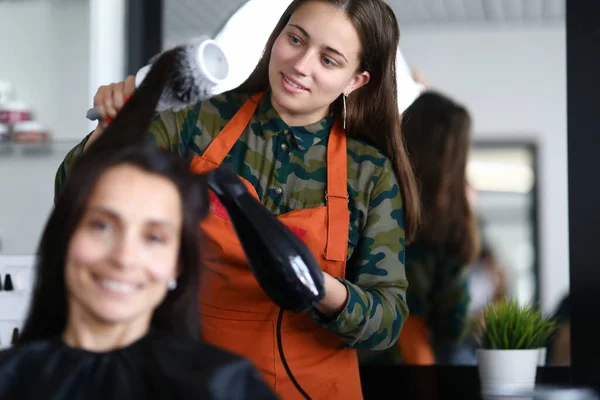 Friseur bringt dem Kunden die Haare und hält Kamm und Haartrockner. — Stockfoto