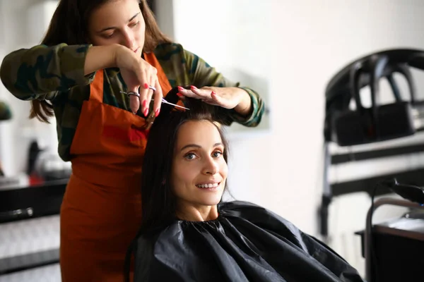 Bella donna tenere ciocca di capelli e tagliare bang con le forbici sul posto di lavoro. — Foto Stock