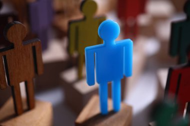 Mavi plastik adam kahverengi ahşap kalabalığa karşı duruyor..