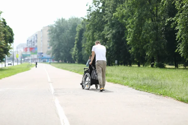 Hombre caminar con mujer en silla de ruedas en el parque . — Foto de Stock