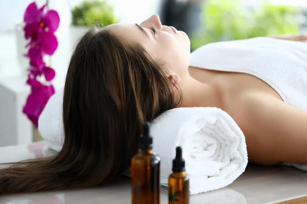 Mulher com cabelo comprido deitado de costas na mesa de massagem com os olhos fechados . — Fotografia de Stock