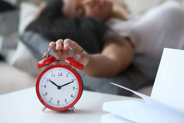 침대에 누워서 자명종 시계를 끄는 여자. — 스톡 사진