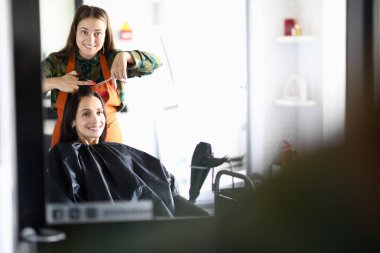 Kuaför ve müşteri aynaya bakıp gülüyorlar.