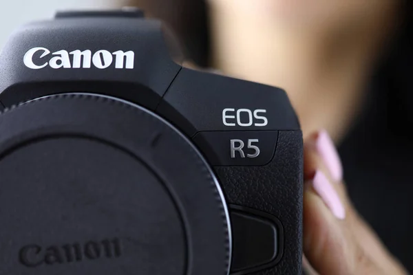 Kobieta trzymać nowy model kanon EOS R5 aparat fotograficzny w ręku zbliżenie — Zdjęcie stockowe