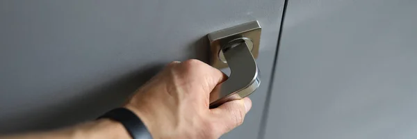 Male hand fitness bracelet opens metal handle door