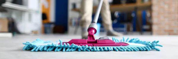 Mano masculina mantenga trapeador de plástico azul contra el primer plano de la oficina moderna — Foto de Stock