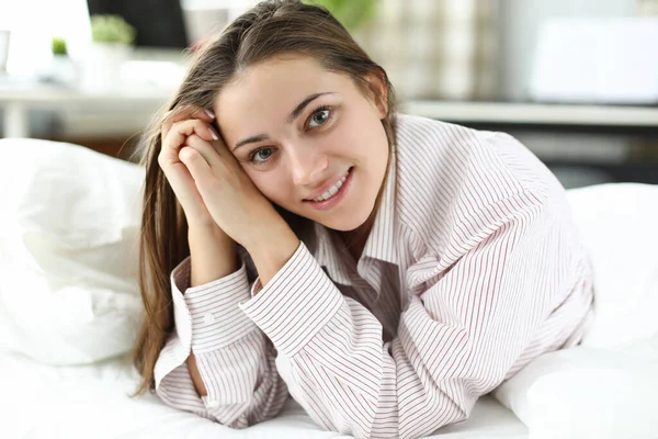 Mujer feliz en una camisa de hombre yace en la cama — Foto de Stock