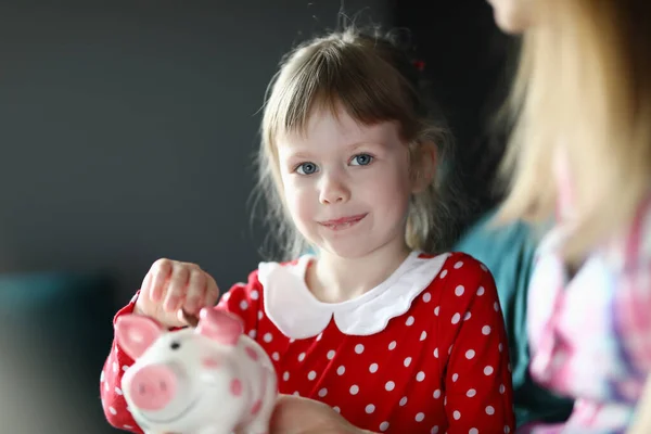 Gelukkig klein meisje zet munten in een spaarvarken bank — Stockfoto