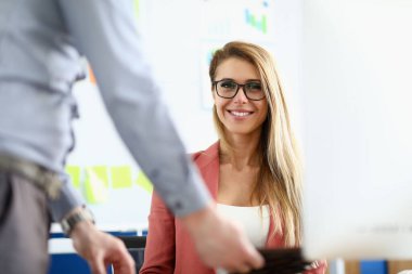 Gözlüklü kadın ofiste oturur ve gülümser.